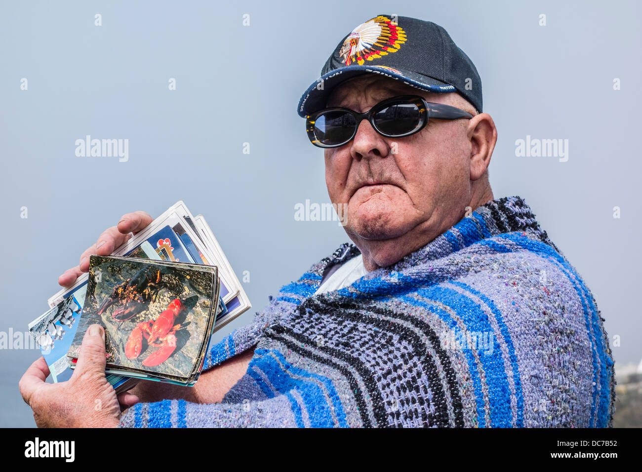 Ralph Skinner verkauft Postkarten an Touristen, eingehüllt in eine indische Decke und Baseball-Cap in Lubec Maine. Stockfoto