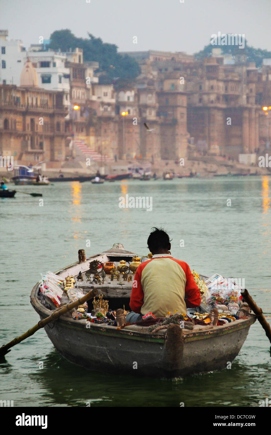 Varanasi, ca. Dec.2010. Ein nicht identifizierter einsamer Fährmann verkaufen Trinckets aus seinem Boot um die Weitergabe von Boote mit Touristen t Stockfoto