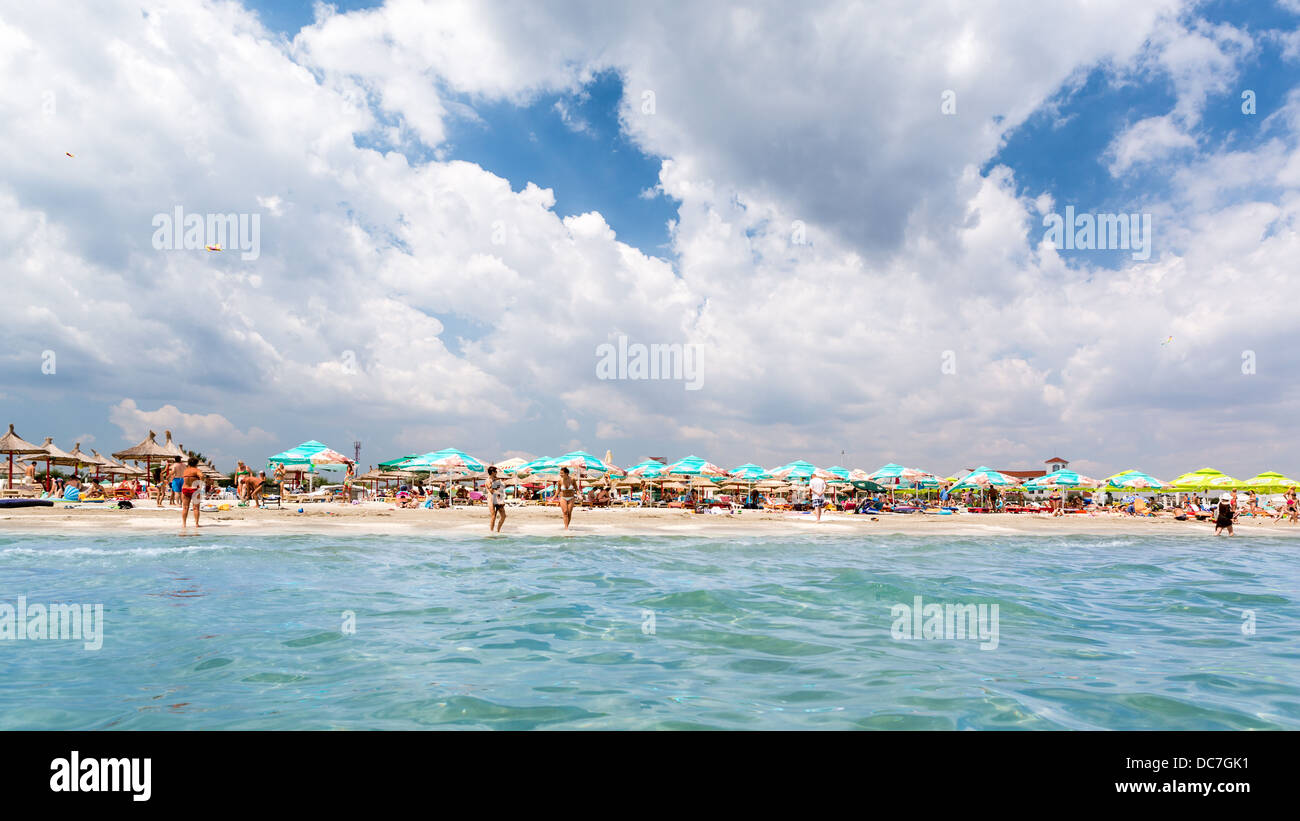 Weiße Wolken und blauer Himmel über einem überfüllten Sandstrand Stockfoto