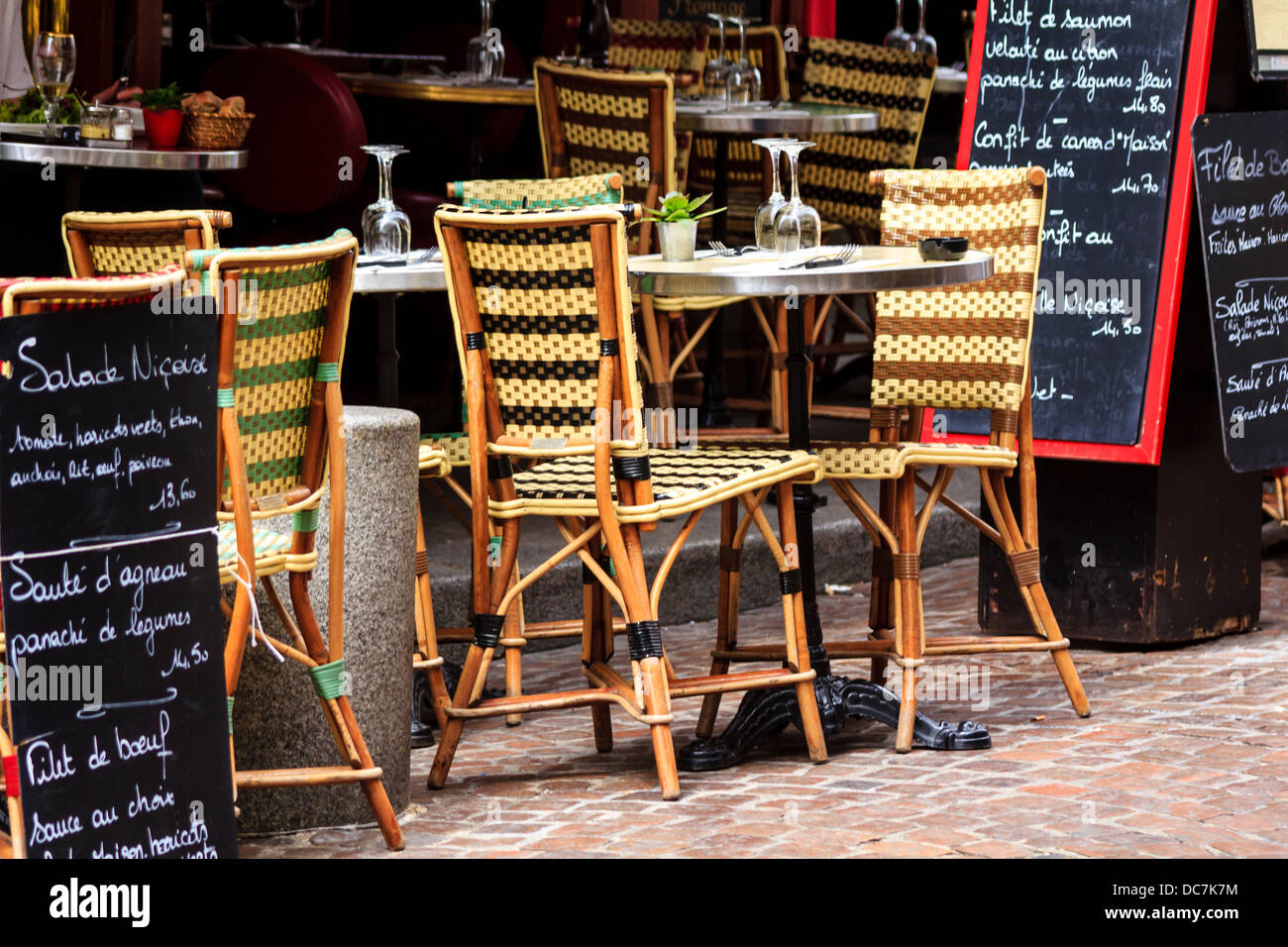 Café in der Rue Mouffetard in Paris, Frankreich / Korbsessel, gepflasterte Straße und Menü-Boards Stockfoto