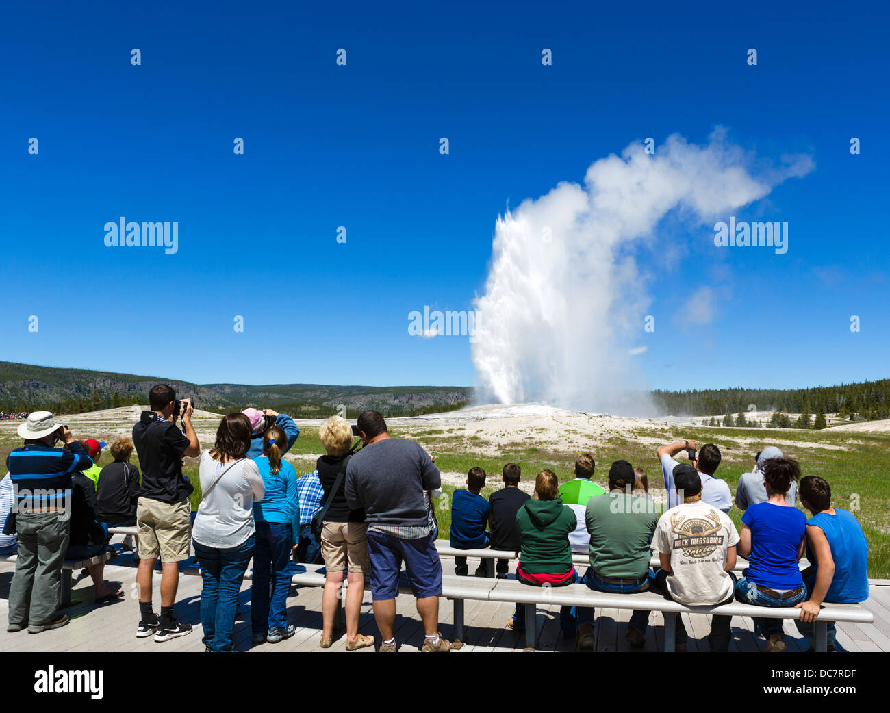 Touristen, die gerade des Ausbruchs des Old Faithful Geysir, Upper Geyser Basin, Yellowstone-Nationalpark, Wyoming, USA Stockfoto
