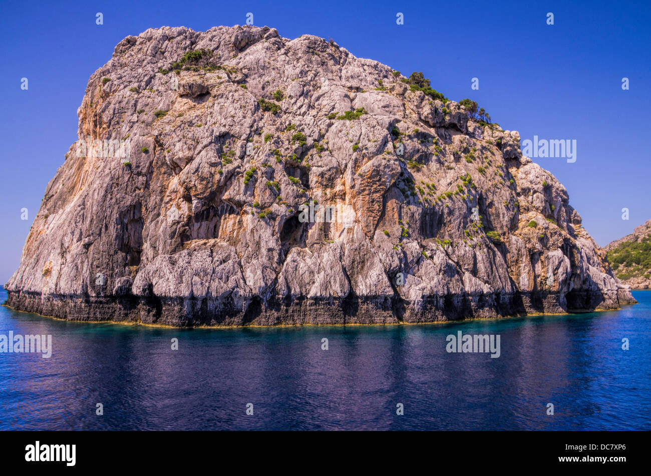 Detailansicht einer tropischen Gezeiten felsige Insel mit Aushöhlung von den Wellen in einem ruhigen blauen Meer Stockfoto