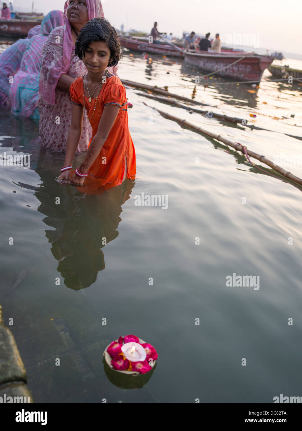 Ein junges Mädchen, ein Pilger zum Fluss Ganges zündet eine Kerze in der Morgendämmerung Ganges Fluss - Varanasi, Indien Stockfoto