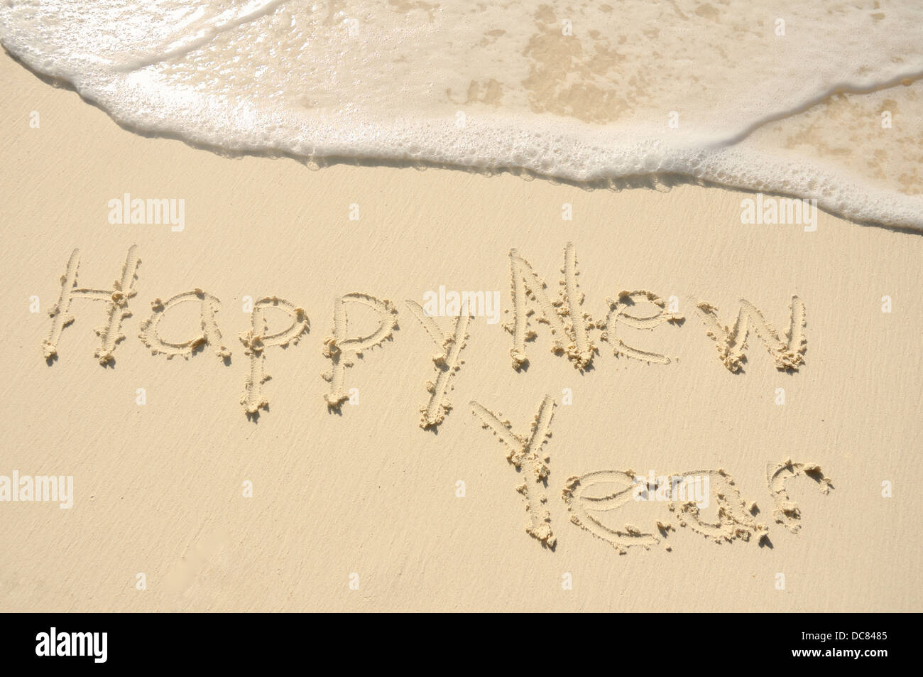 Die Phrase "Frohes neues Jahr", geschrieben in den Sand am Strand Stockfoto