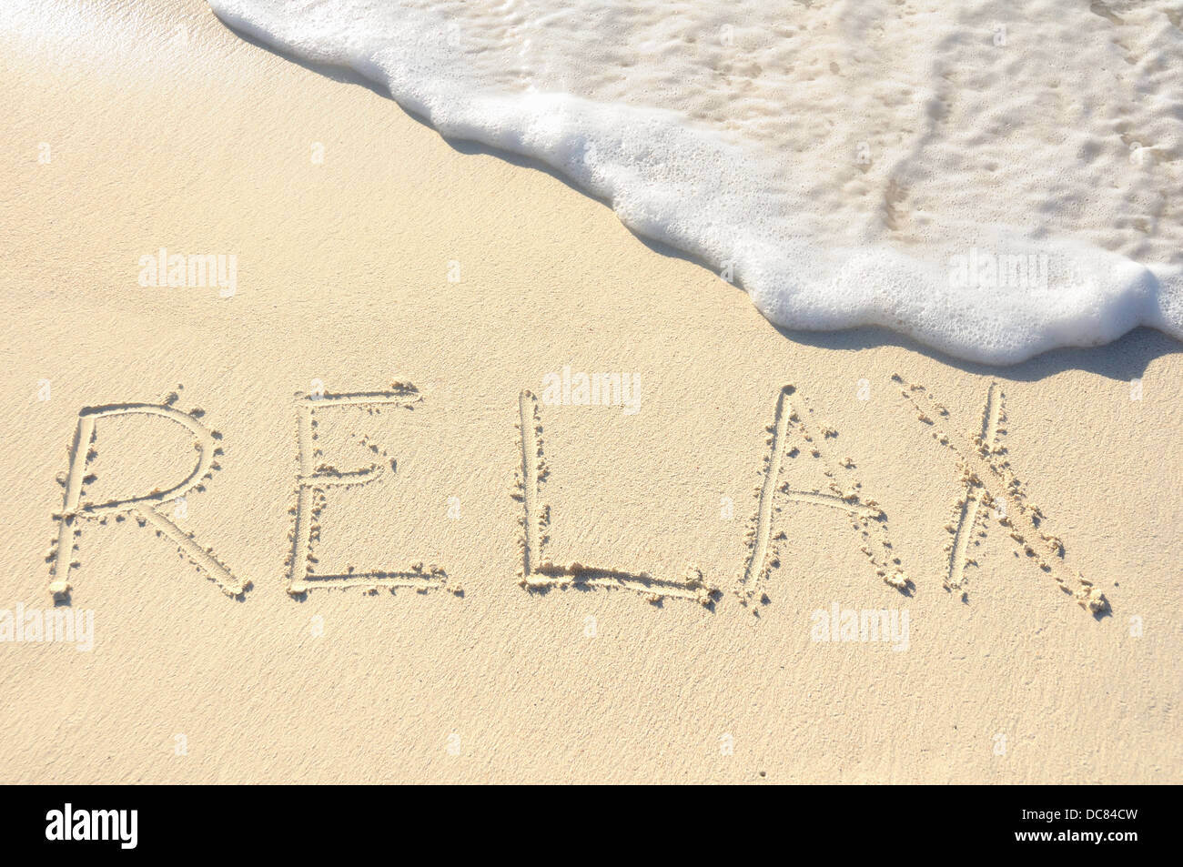 Das Wort "entspannen" in den Sand am Strand geschrieben Stockfoto