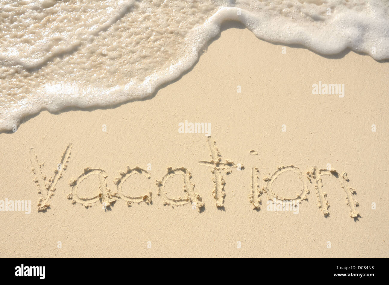 Das Wort "Urlaub" an einem Strand in den Sand geschrieben Stockfoto