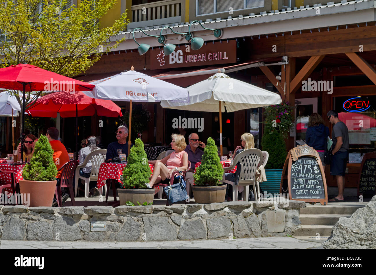 Outdoor-Gäste an Tischen in Restaurants und Cafés in Whistler Village im Sommer.  Unter freiem Himmel im Sommer auf der Terrasse speisen. Stockfoto