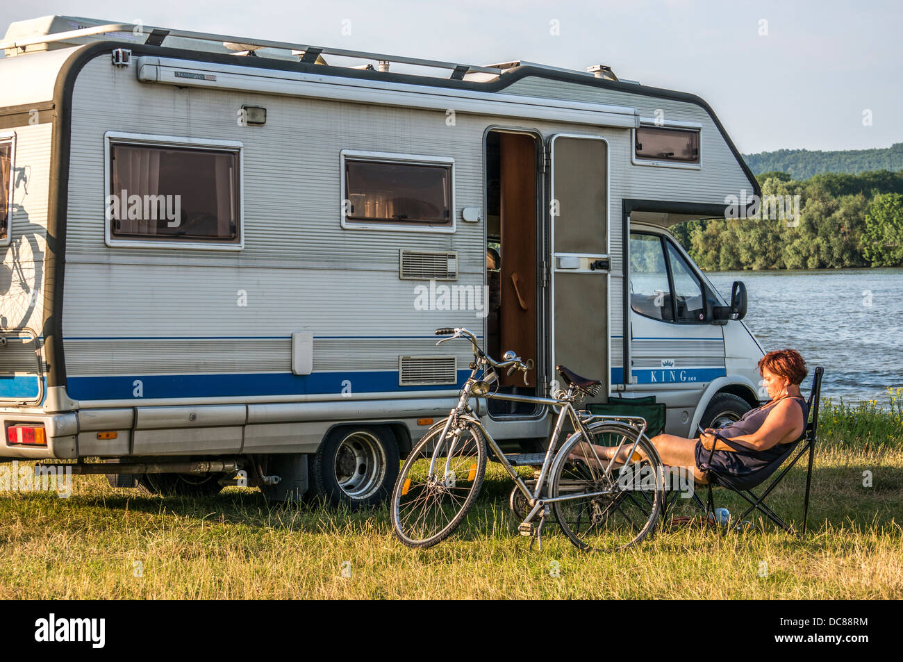 Frau entspannende außerhalb ihrer Reisemobil auf dem Aire de camping-car, La Mailleraye-sur-Seine, Seine-Maritime, Rhône, Nordfrankreich, Europa. Stockfoto