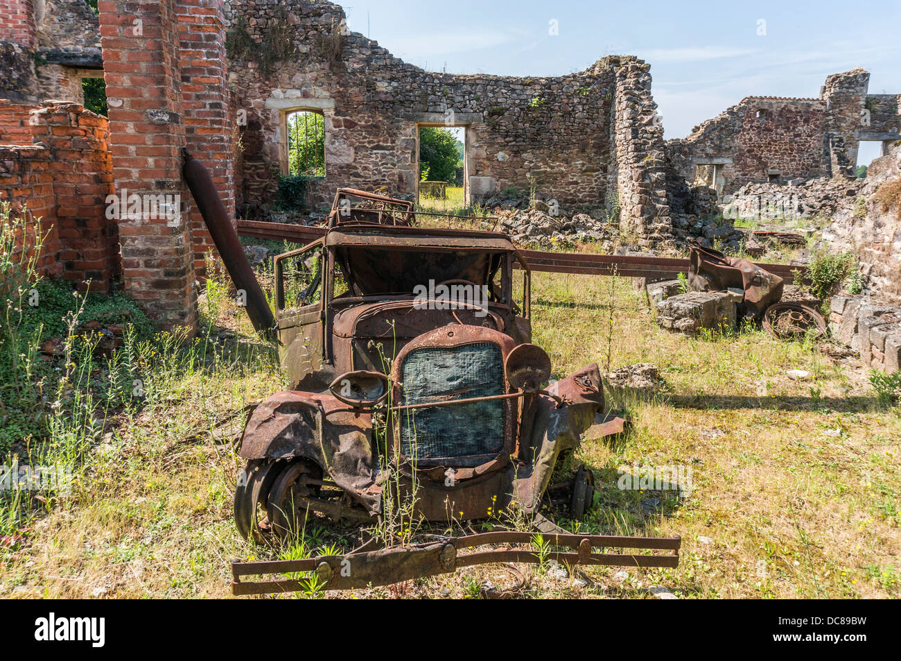 Eine verrostete Auto und verfallene Gebäude, in die Ruinen von Oradour-sur-Glane, Krieg, Massaker, Dordogne, Limousin, West, Südfrankreich. Stockfoto