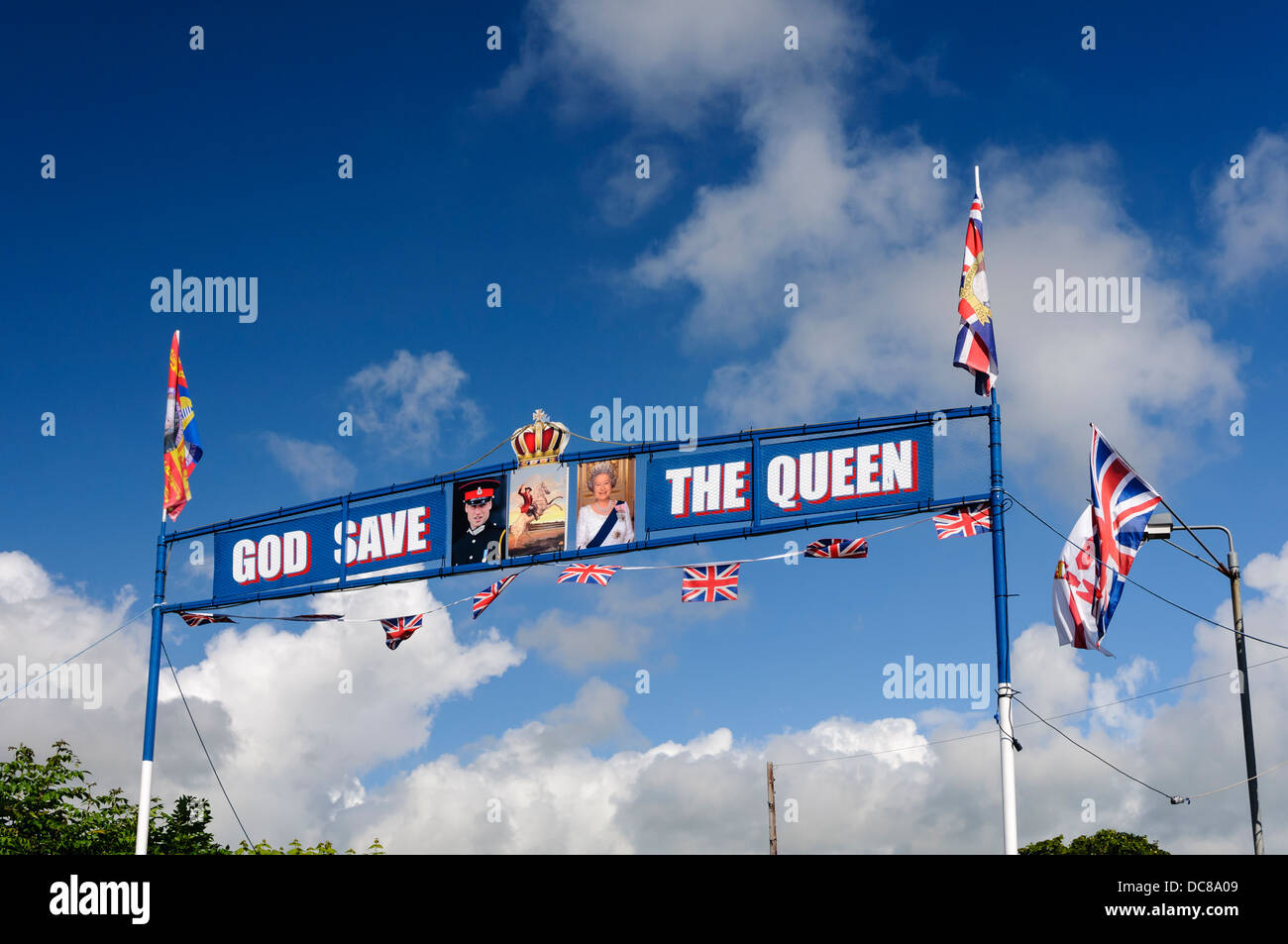 Eine Orange Bogen über eine Straße in Kilkeel mit Fahnen, Fotos von der Queen und Prinz William, mit "God Save The Queen" Stockfoto