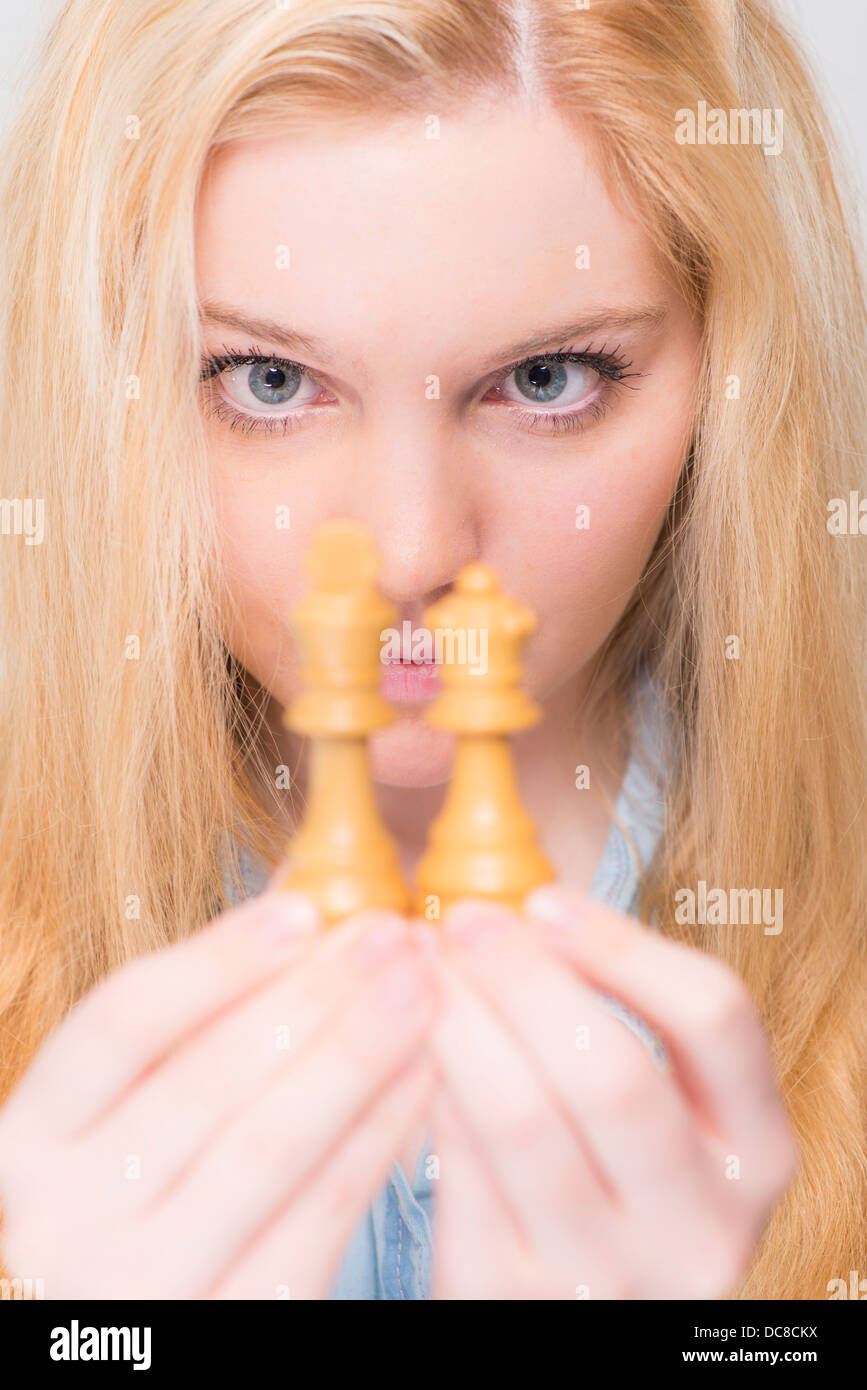 Junge blonde Frau, die eng mit Blick auf Schachfiguren Stockfoto