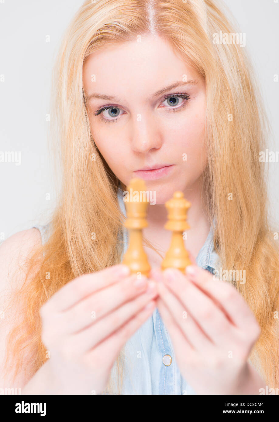 Junge blonde Frau, die eng mit Blick auf Schachfiguren Stockfoto