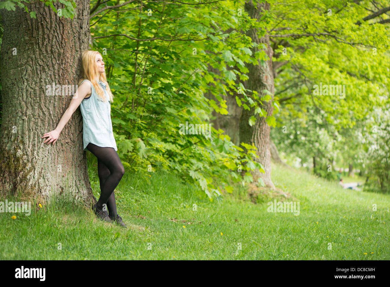 Natur-Szene mit einer jungen attraktiven Frau lehnte sich gegen einen Baum in einem park Stockfoto