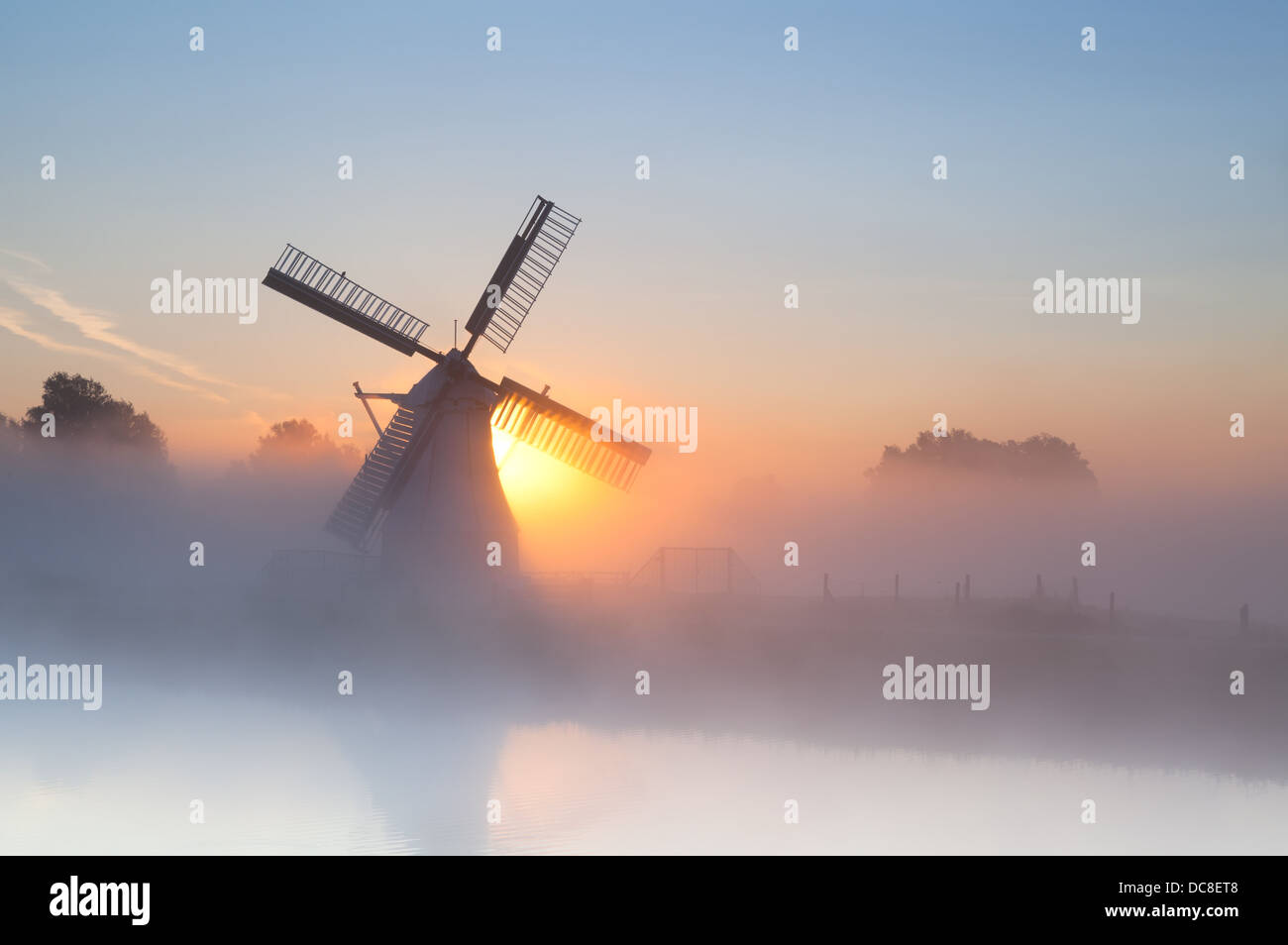 Holländische Windmühle im dichten Nebel bei Sonnenaufgang Stockfoto
