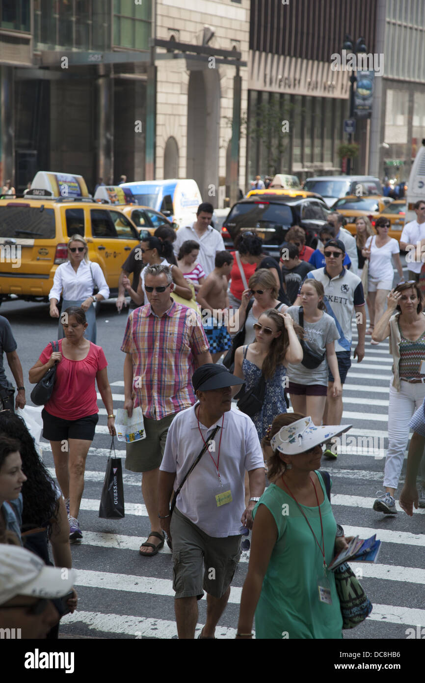 Menschen überqueren die Straße an der immer überfüllten Kreuzung 5th Avenue & 42nd Street, New York City. Stockfoto
