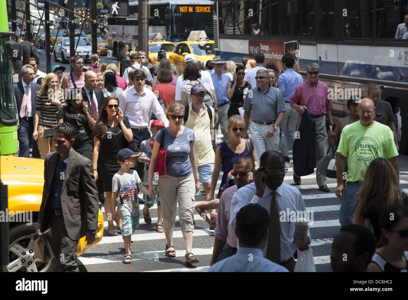 Menschen überqueren die Straße an der immer überfüllten Kreuzung 5th Avenue & 42nd Street, New York City. Stockfoto