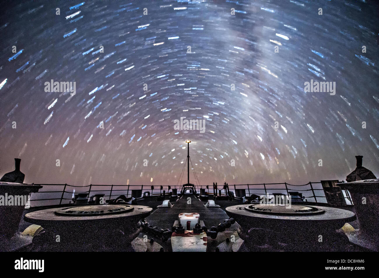 Eine extreme Nacht Ausstellung zeigt Sternspuren als uns Navy Dock Landung Schiff, die USS Germantown Transite im Korallenmeer 10. August 2013 Segeln im Korallenmeer. Stockfoto