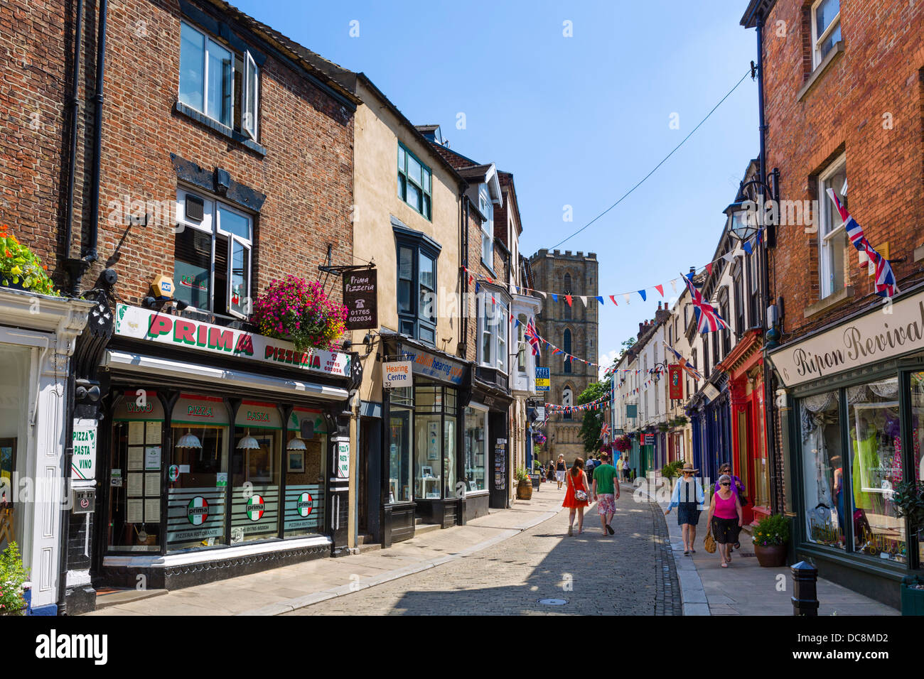 Geschäfte im historischen Kirkgate im Stadtzentrum mit Blick auf die Kathedrale, Ripon, North Yorkshire, England, Großbritannien Stockfoto
