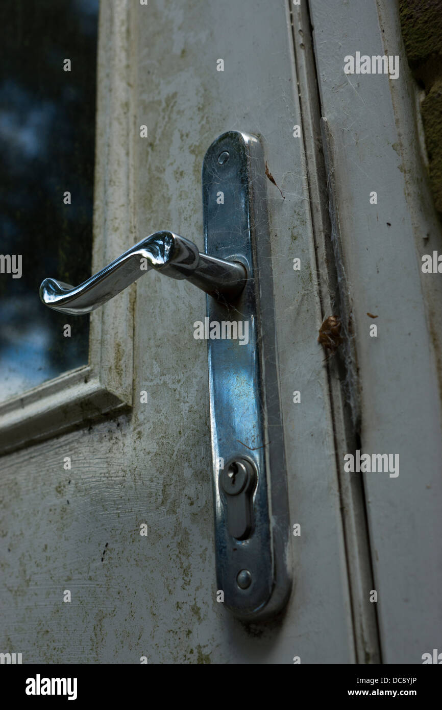 Chrome Tür Griff Cob Stege, die Tastensperre Glas glänzend reflektierende schmutzig Grass Flecken verwitterte Tür Stockfoto