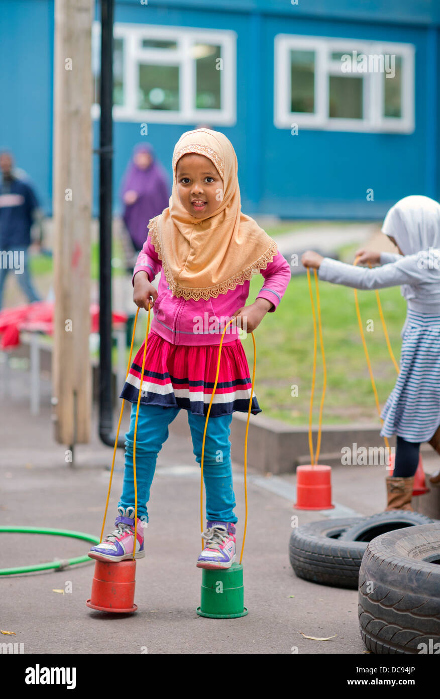 Der St.-Pauls-Kindergarten und das Kinderhaus, Bristol UK - A somalische Mädchen auf Stelzen auf dem Spielplatz spielen. Stockfoto