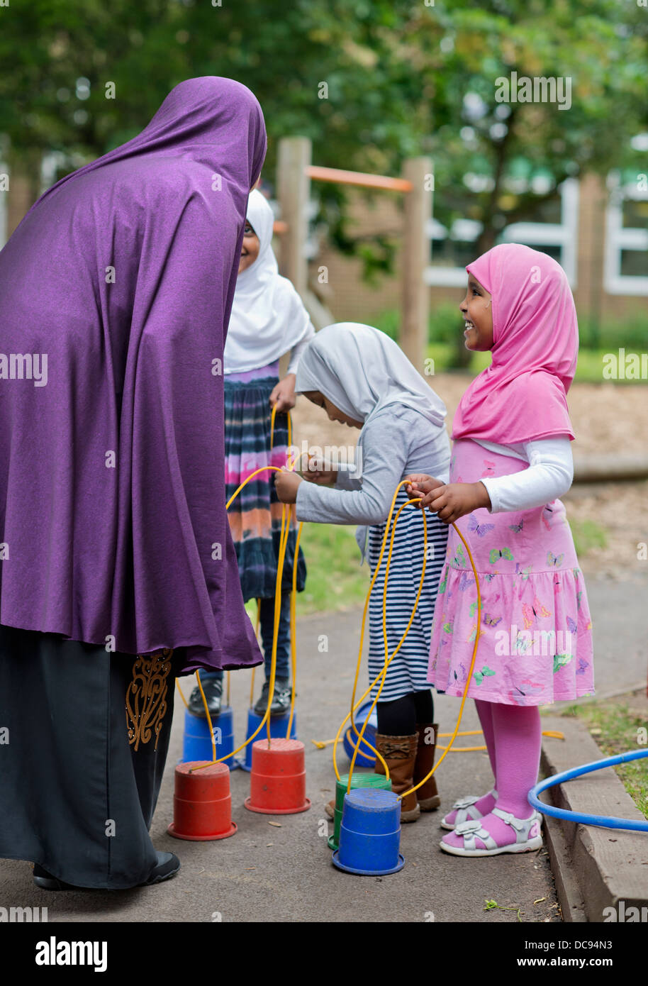 Der Kindergarten St. Pauls und Kinderhaus, Bristol UK - somalische Mädchen auf Stelzen auf dem Spielplatz spielen. Stockfoto