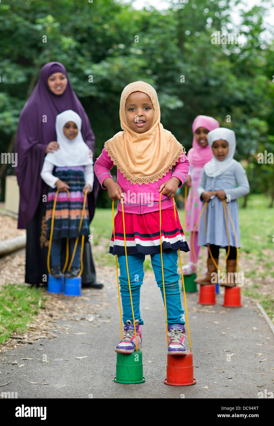 Der Kindergarten St. Pauls und Kinderhaus, Bristol UK - somalische Mädchen auf Stelzen auf dem Spielplatz spielen. Stockfoto