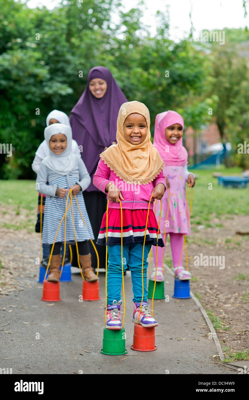 Der Kindergarten St. Pauls und Kinderhaus, Bristol UK - somalische Mädchen auf Stelzen auf dem Spielplatz spielen. Stockfoto