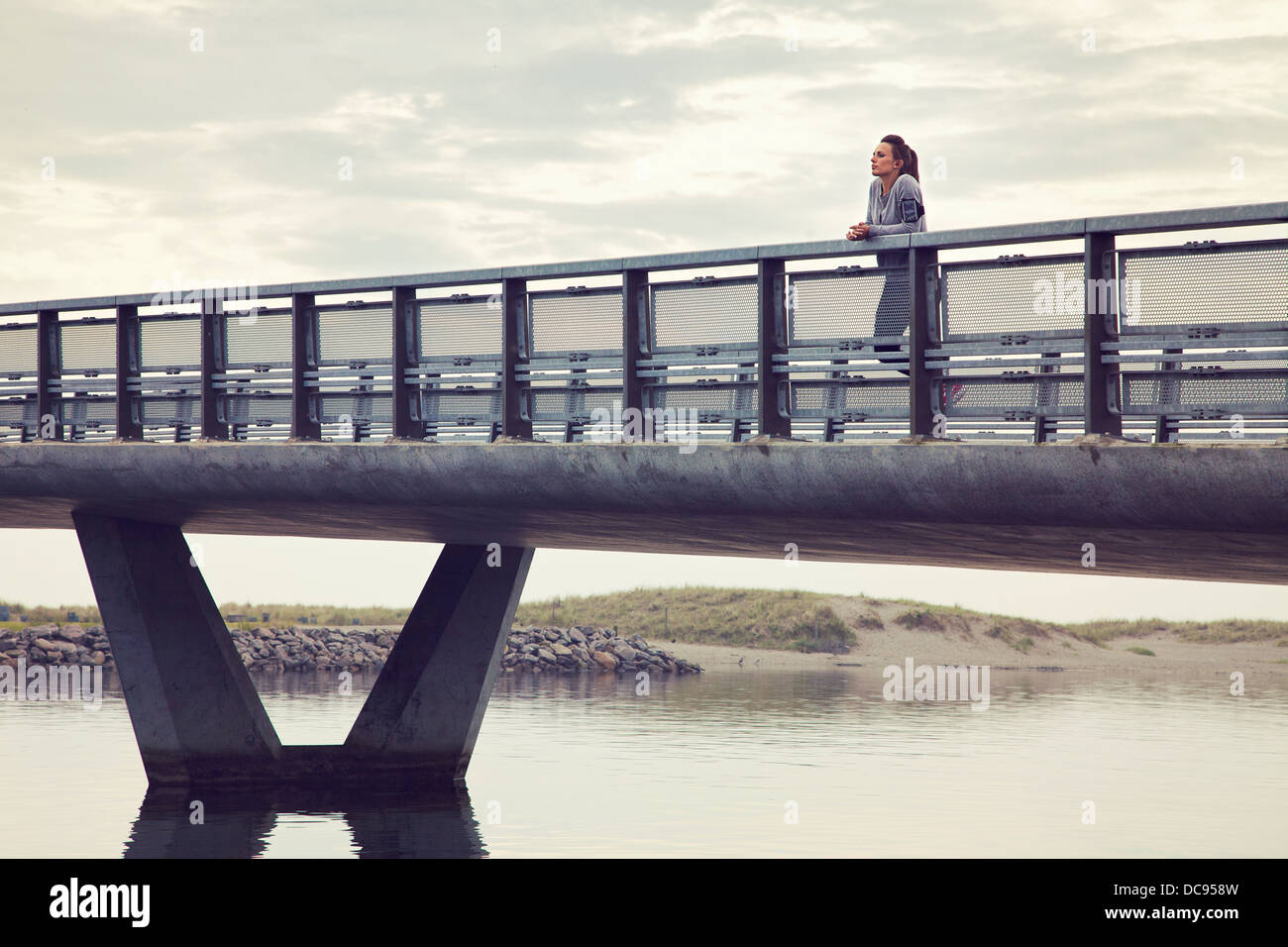 Frau allein auf der Brücke gegen bewölktem Himmel Stockfoto