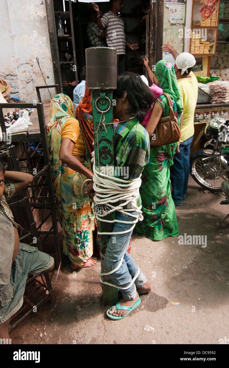 Teenager, angebunden an einen Metallpfosten Stockfoto