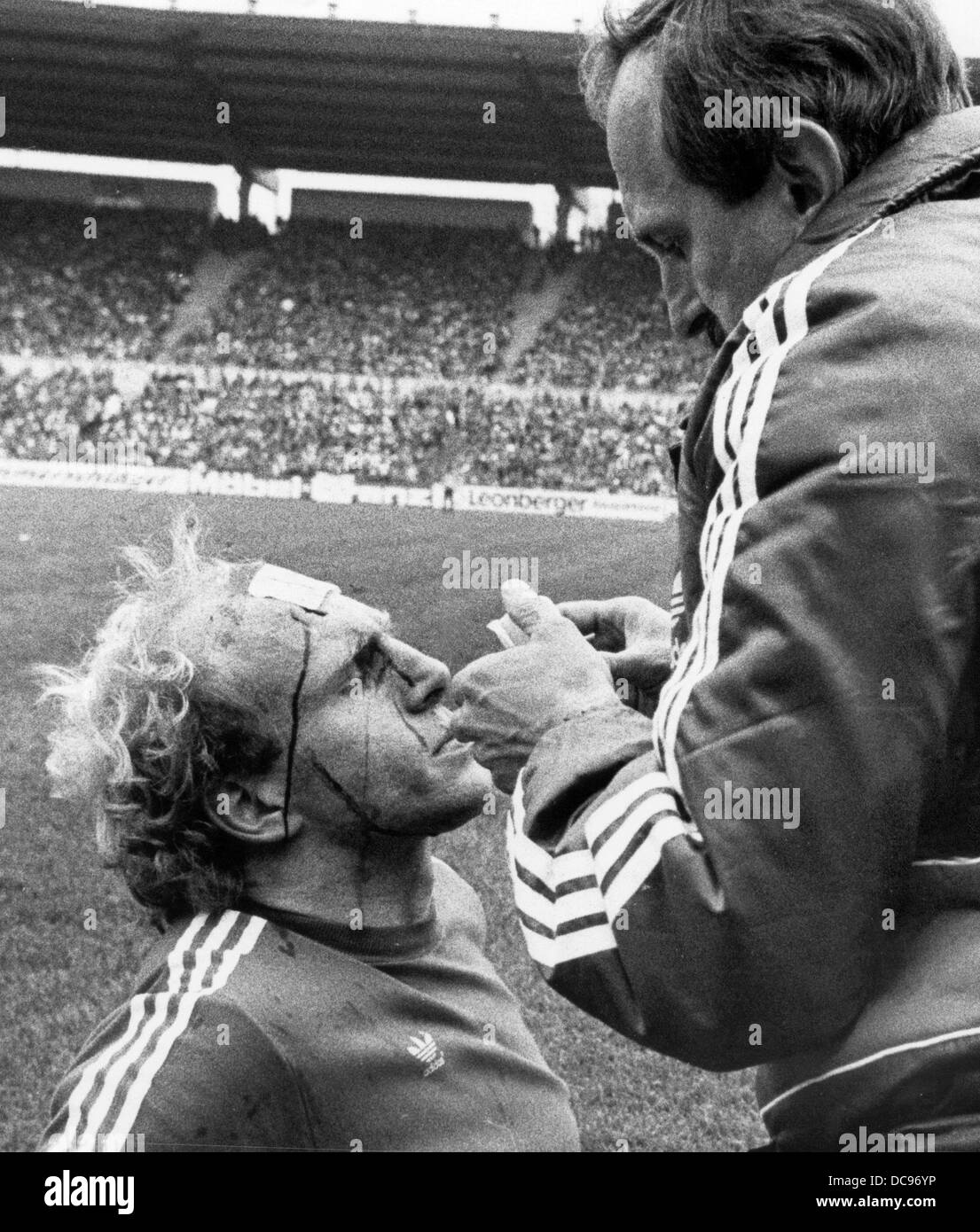Stürmer des FC Bayern München Dieter Hoeneß (l) wird am 1. Mai 1982 an der Seite des Feldes behandelt. Stockfoto