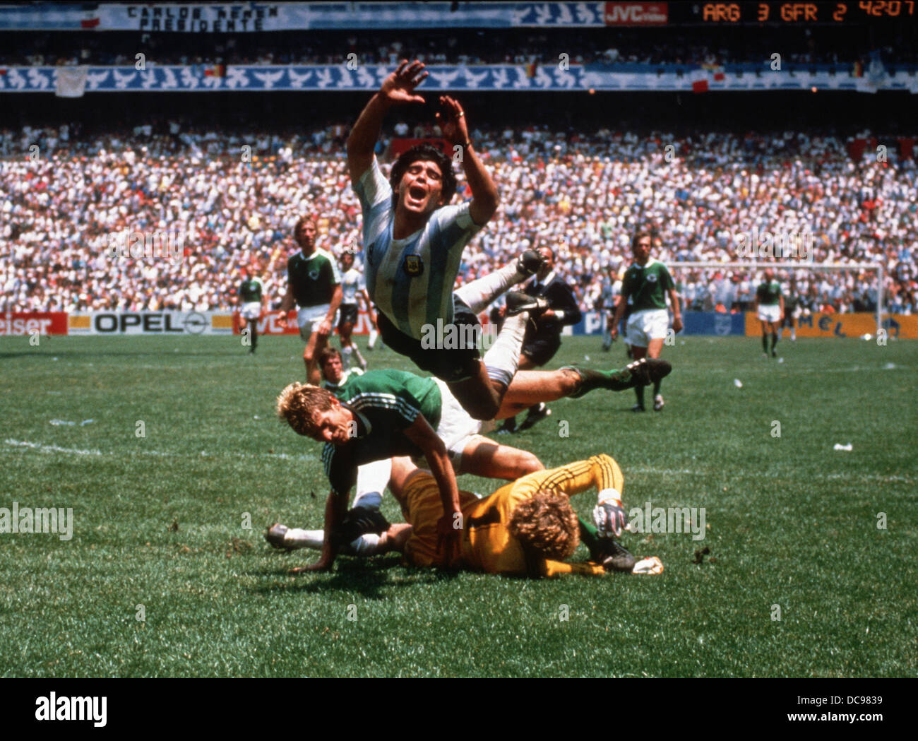Argentinische Fußball-Nationalspieler Diego Maradona fällt über deutsche Spieler Harald "Toni" Schumacher (gelb) und Karl-Heinz Förster (grün) am 29. Juni 1986 während des Finales der Fußball-WM in Mexiko. Stockfoto