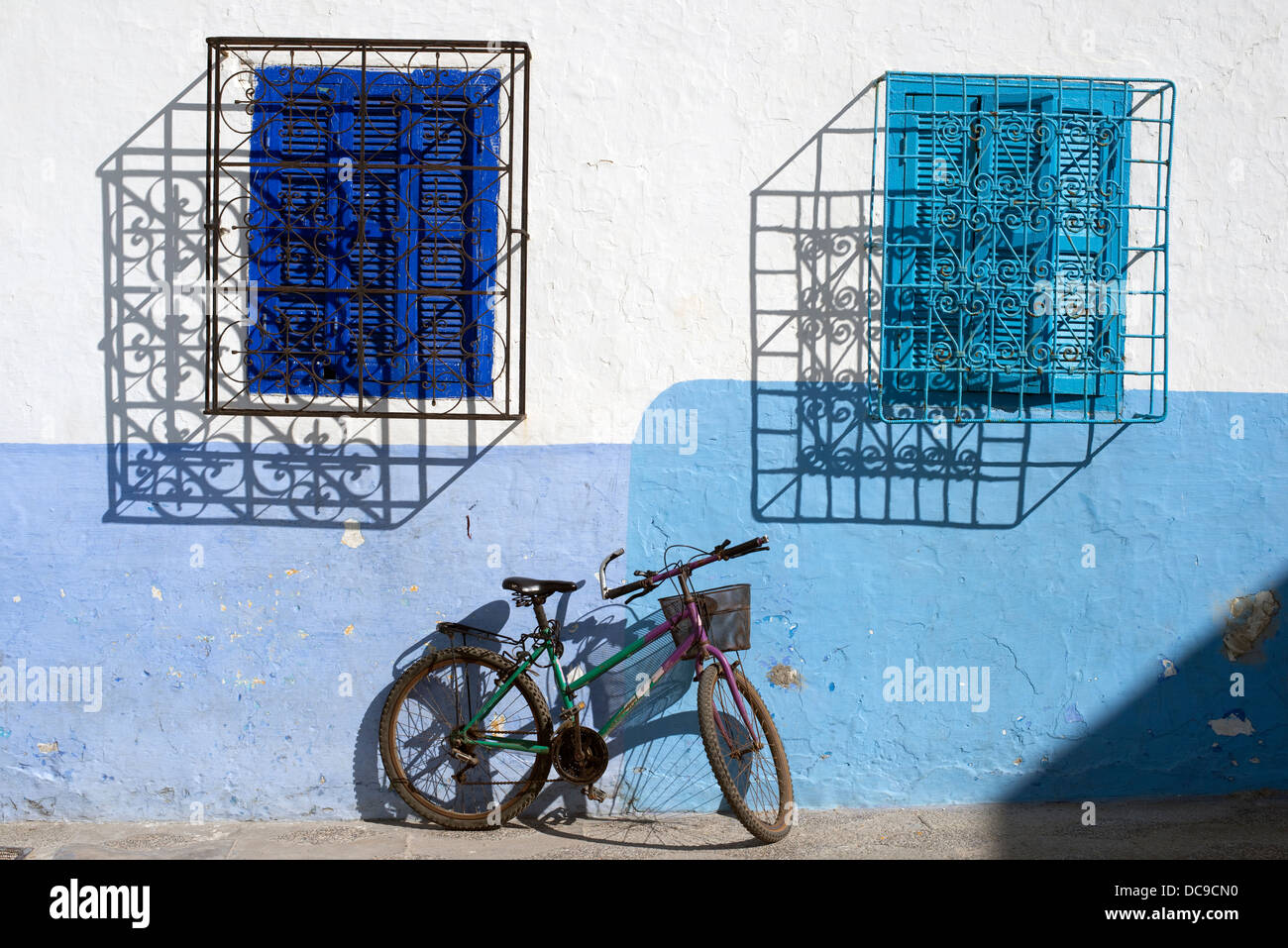 Eine abstrakte Blick auf zwei Fenster und ein Fahrrad in der Küstenstadt Stadt Asilah, Marokko. Stockfoto