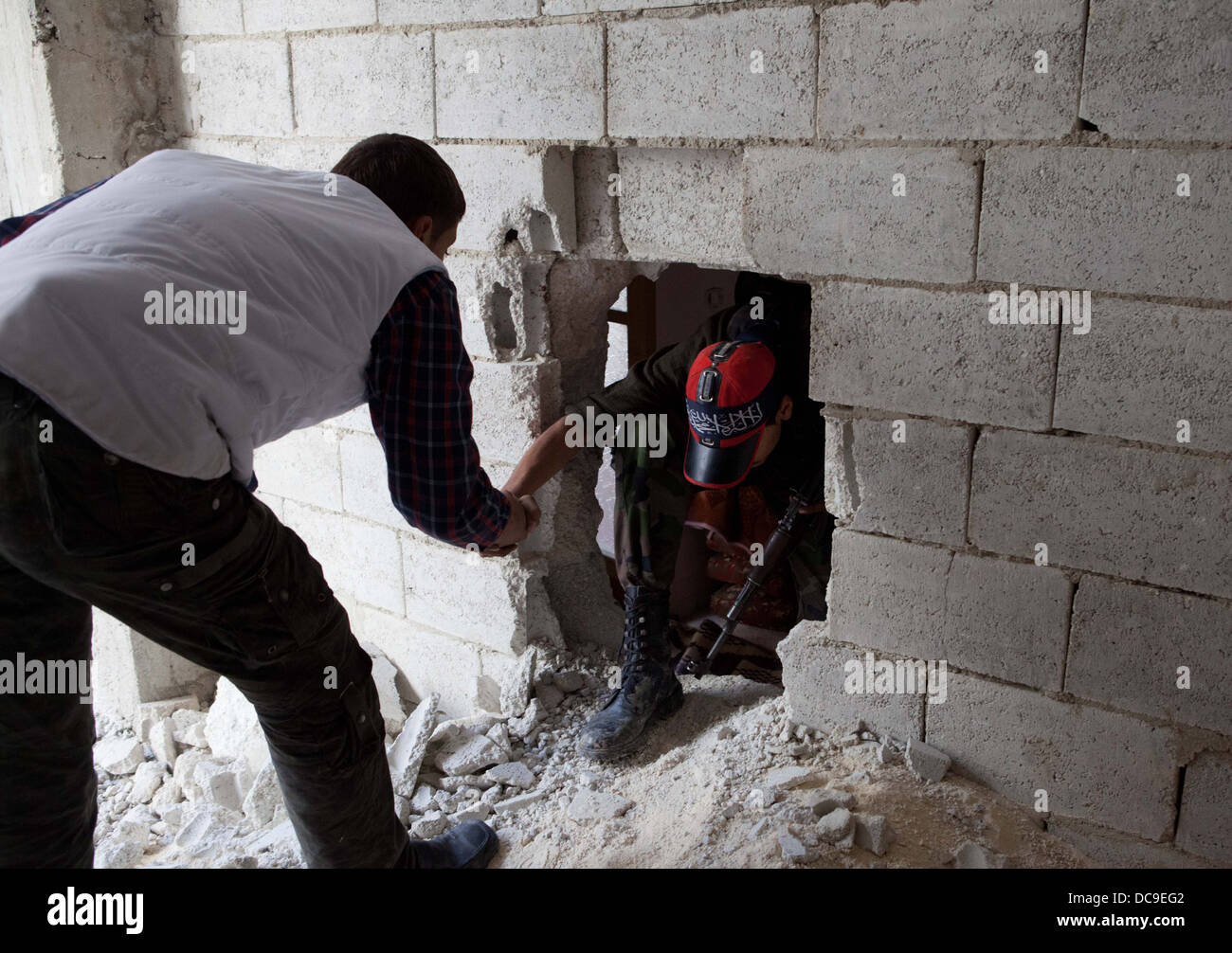 Ein freie Syran Armee Kämpfer bekommt Hilfe durch Löcher in den Wänden in Amaria klettern. Viele Häuser hatten Löcher in der Wand. Stockfoto