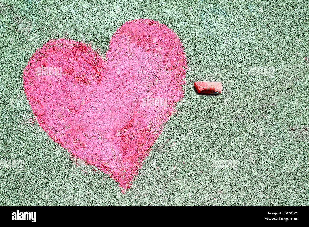 ein rosa Herz-Symbol wird auf einem Bürgersteig außerhalb mit Kreide gezeichnet. Stockfoto