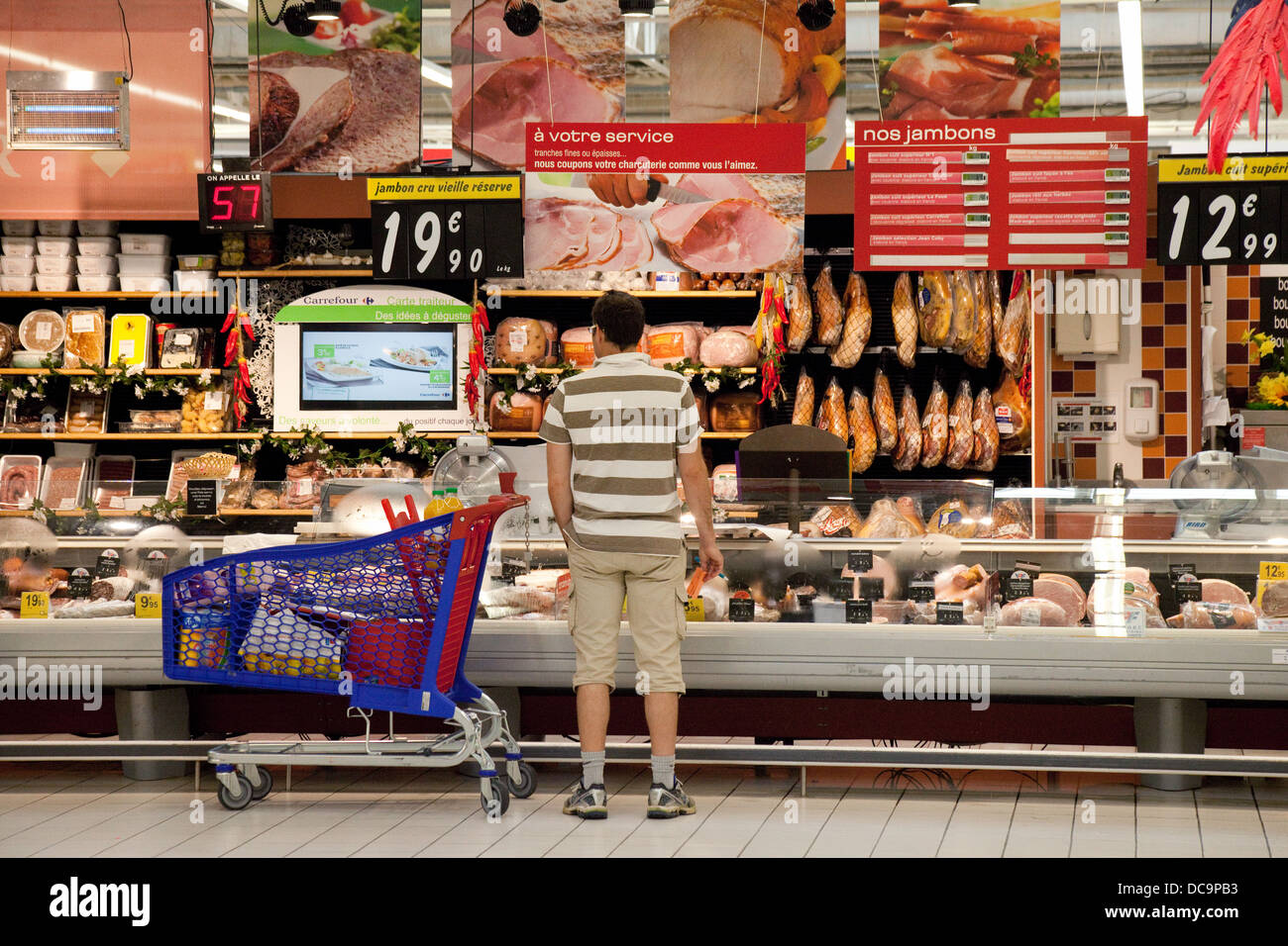 Ein Mann an der Fleischtheke (Boucherie) einkaufen, französische Carrefour Supermarkt, Dordogne, Frankreich Europa Stockfoto