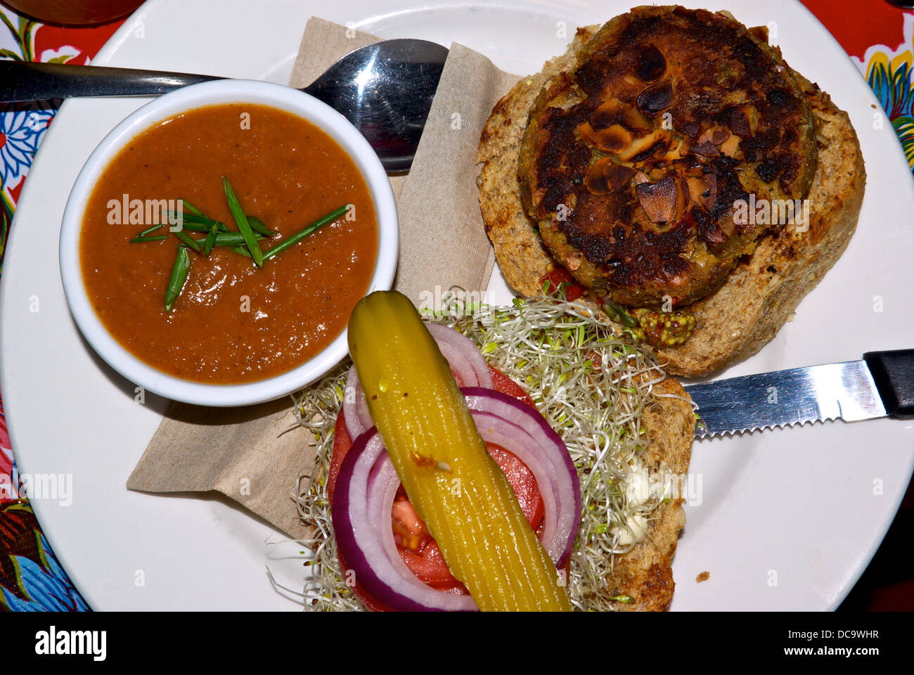 Gebratene Mandeln vegetarische Burger getoasteten Brötchen Alfalfa Sprossen rote Scheibe Zwiebel Dill Pickles Seite Schüssel Kartoffel Paprika Tomatensuppe Stockfoto