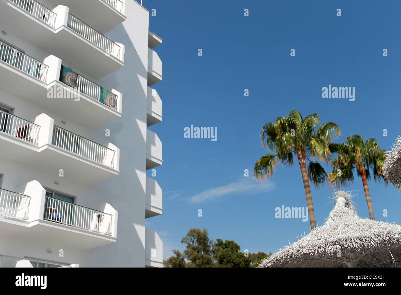 Weiße spanische Touristenhotel mit Palmen und Sonnenschirmen, Mallorca, Spanien. Stockfoto