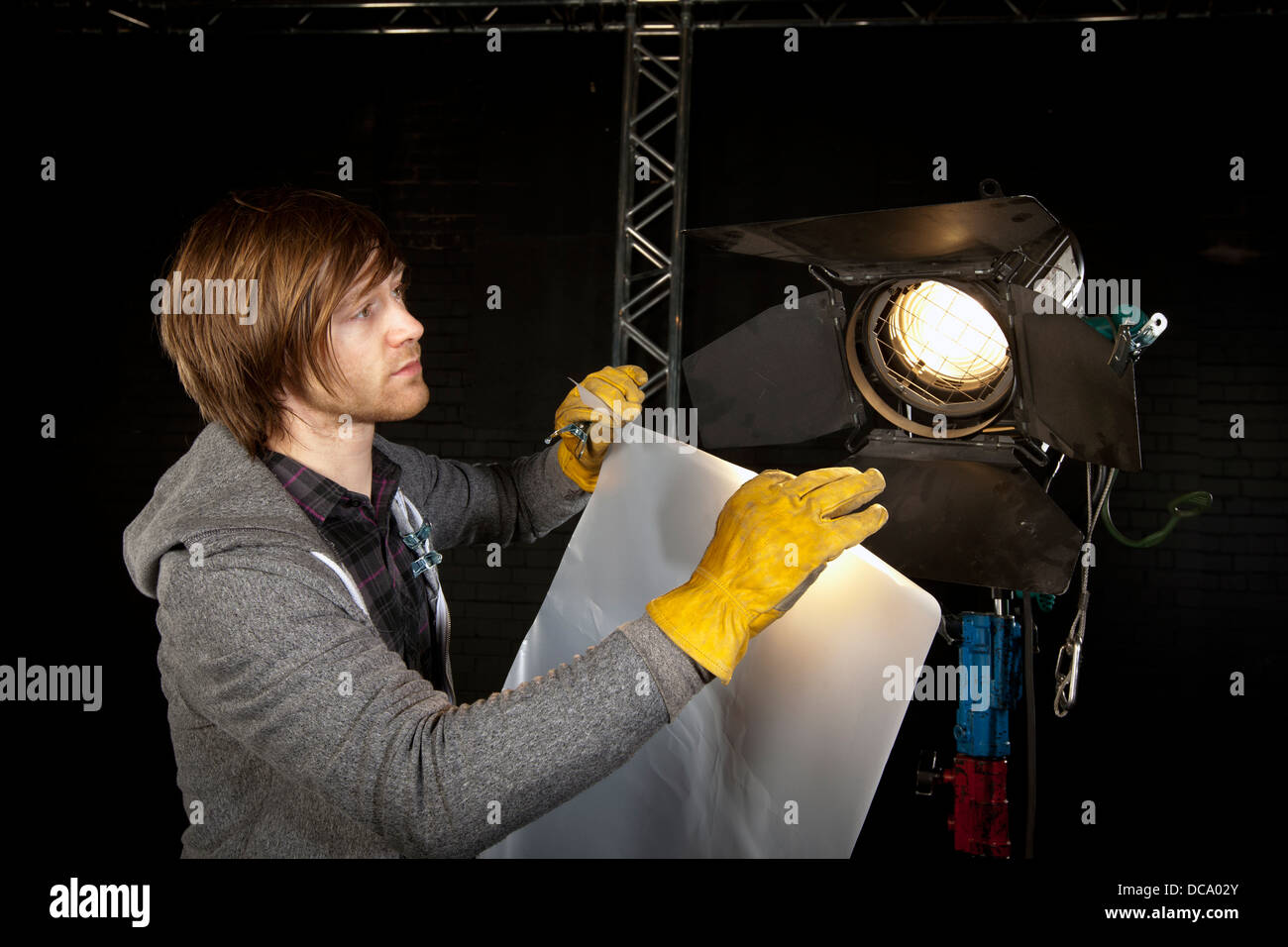 Mann ein Studiolicht in ein Fernsehstudio Diffusor Inverkehrbringen Beleuchtung. Stockfoto
