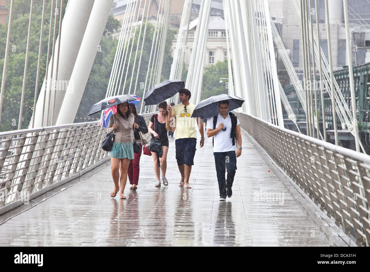 Touristen, die Überquerung der Golden Jubilee Fußgängerbrücke im Regen, London, England Stockfoto