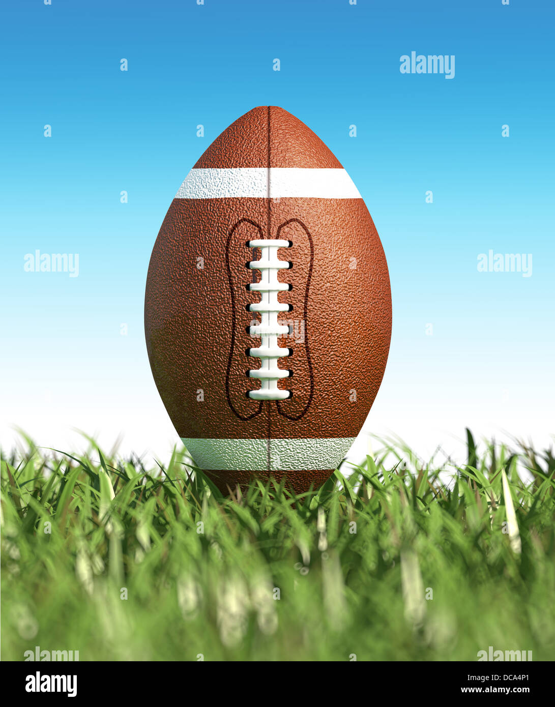 Amerikanischer Fußball auf dem Rasen, mit blauem Himmel im Hintergrund, keine Wolken. Seitenansicht vom Boden. Stockfoto