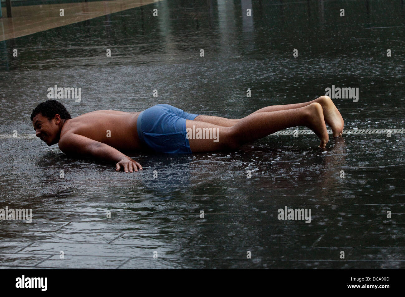 Ein junger Mann verlegen auf dem Bürgersteig In der Regen, der South Bank, London, England Stockfoto