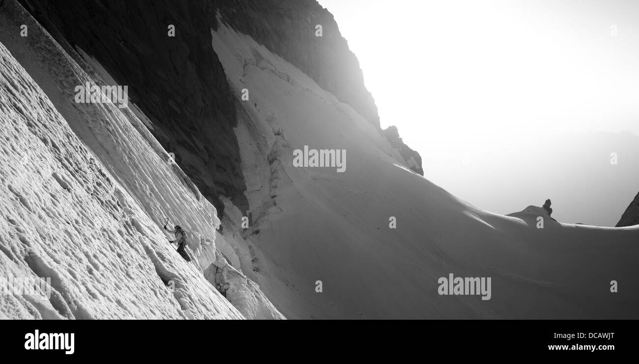 B&w Panorama Fotografie. alpinist ist Schnee steilen Hang. Sonnenschein und Schnee Crest ist im Hintergrund sichtbar. Stockfoto