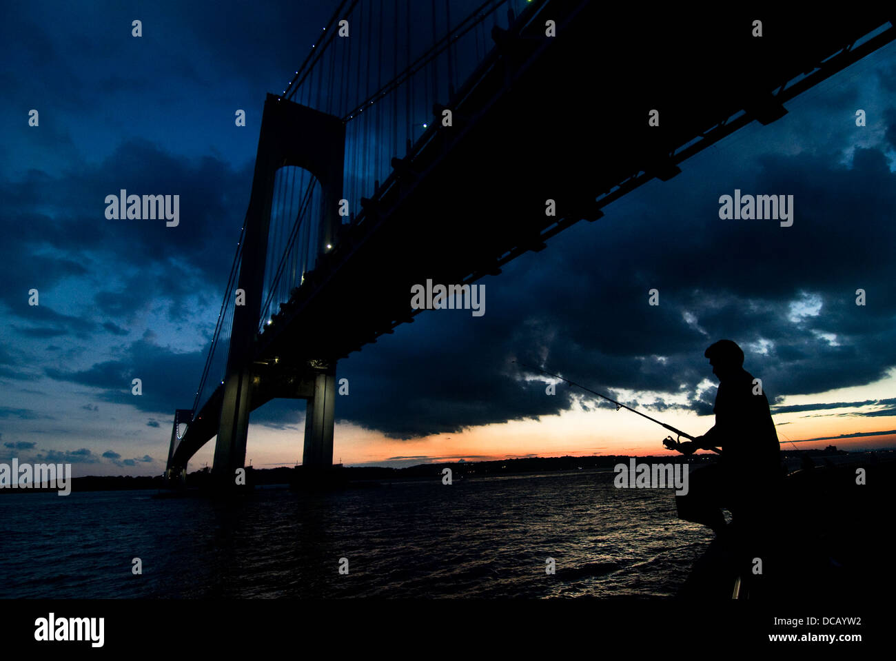 Ein Fischer angeln unter der Verrazano-Brücke in New York. Stockfoto