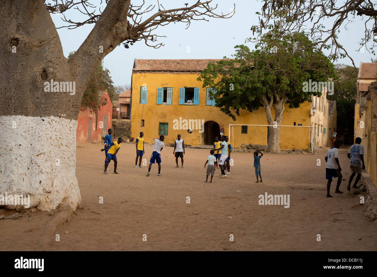 Junge Männer mit Fußball, am späten Nachmittag zu spielen. Goree Island, Senegal. Baobab auf linken Seite. Stockfoto