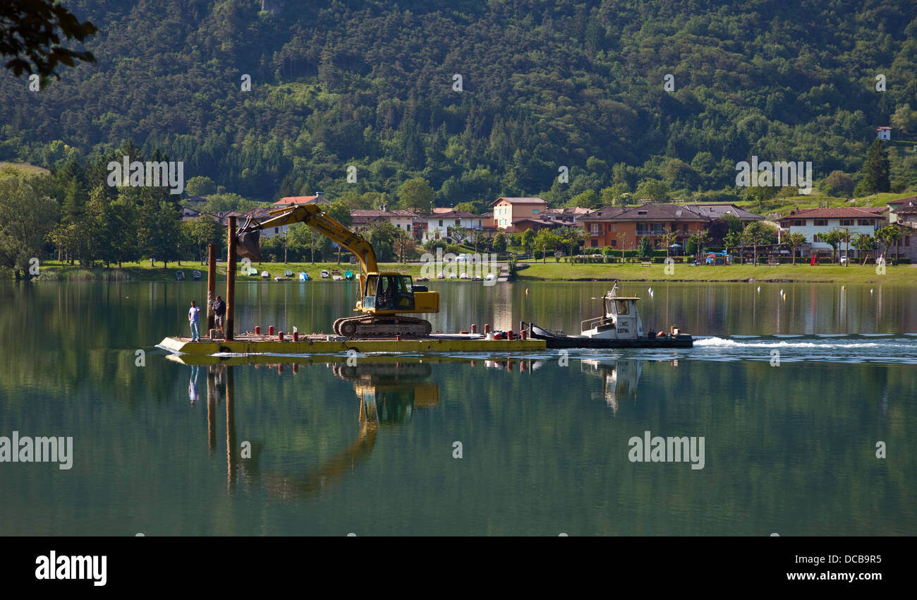 Mechanische Digger beförderten auf Floß über eine Tug Boat, Idrosee, Italien Stockfoto