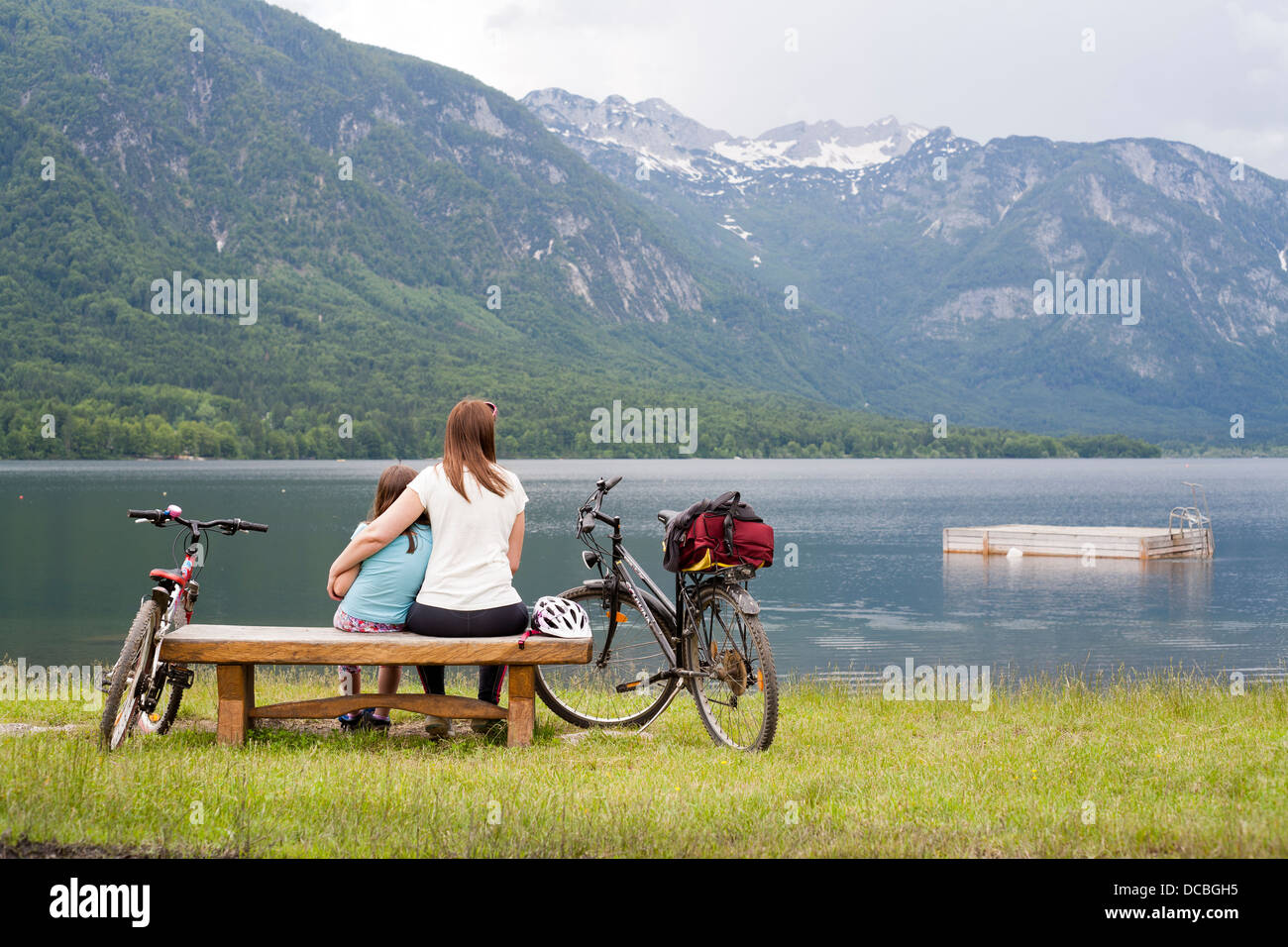 Mutter und Tochter zusammen sitzt auf einer Holzbank von Bohinj-See, Gorenjska Julischen Alpen in Slowenien. Stockfoto