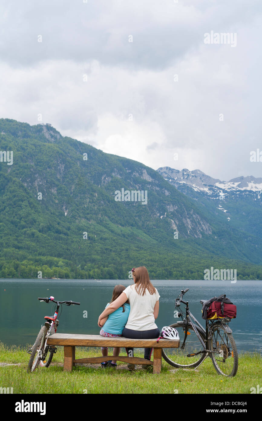 Mutter und Tochter zusammen sitzt auf einer Holzbank von Bohinj-See, Gorenjska Julischen Alpen in Slowenien. Stockfoto