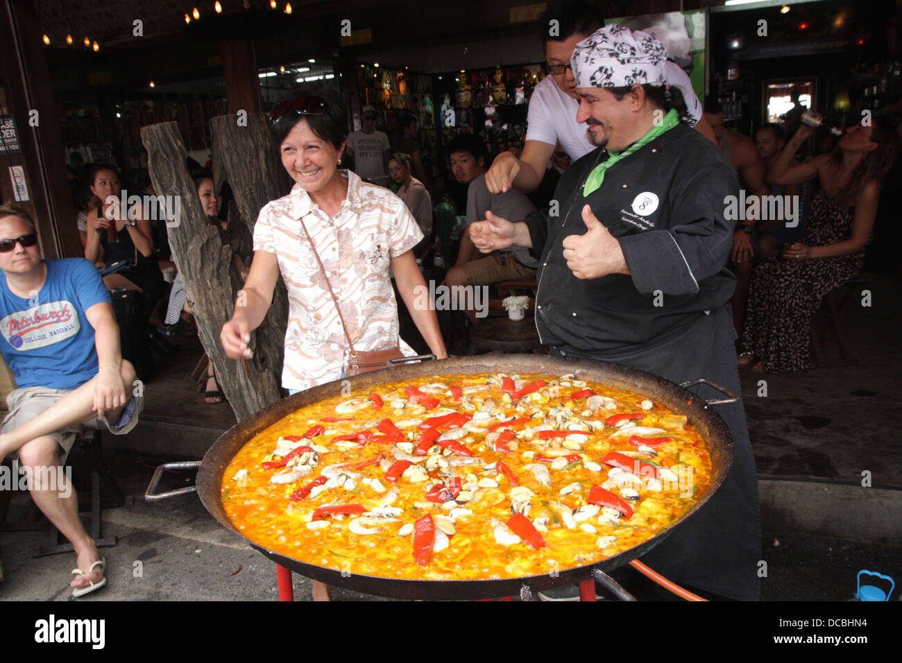 Viva 8 Chef posiert Kunden in der Nähe von Meer Essen Paella Pfanne, Wochenendmarkt Chatuchak, Bangkok, Thailand Stockfoto
