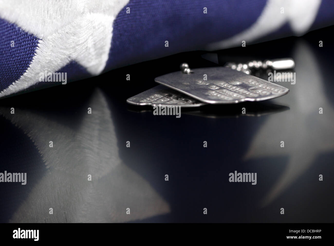 Dog Tags oder ID-Tags, einmal getragen von einem militärischen Veteran mit einem gefalteten US-Flagge Stockfoto