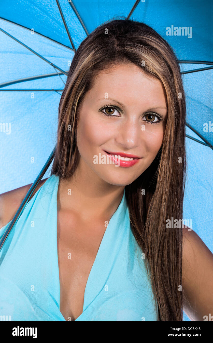 Junge Frau im blauen Kleid mit blauen Schirm Stockfoto
